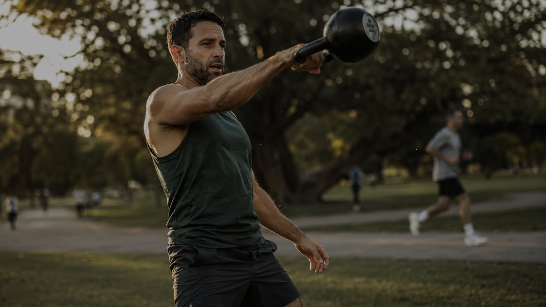 Man exercising with a kettlebell in a park setting